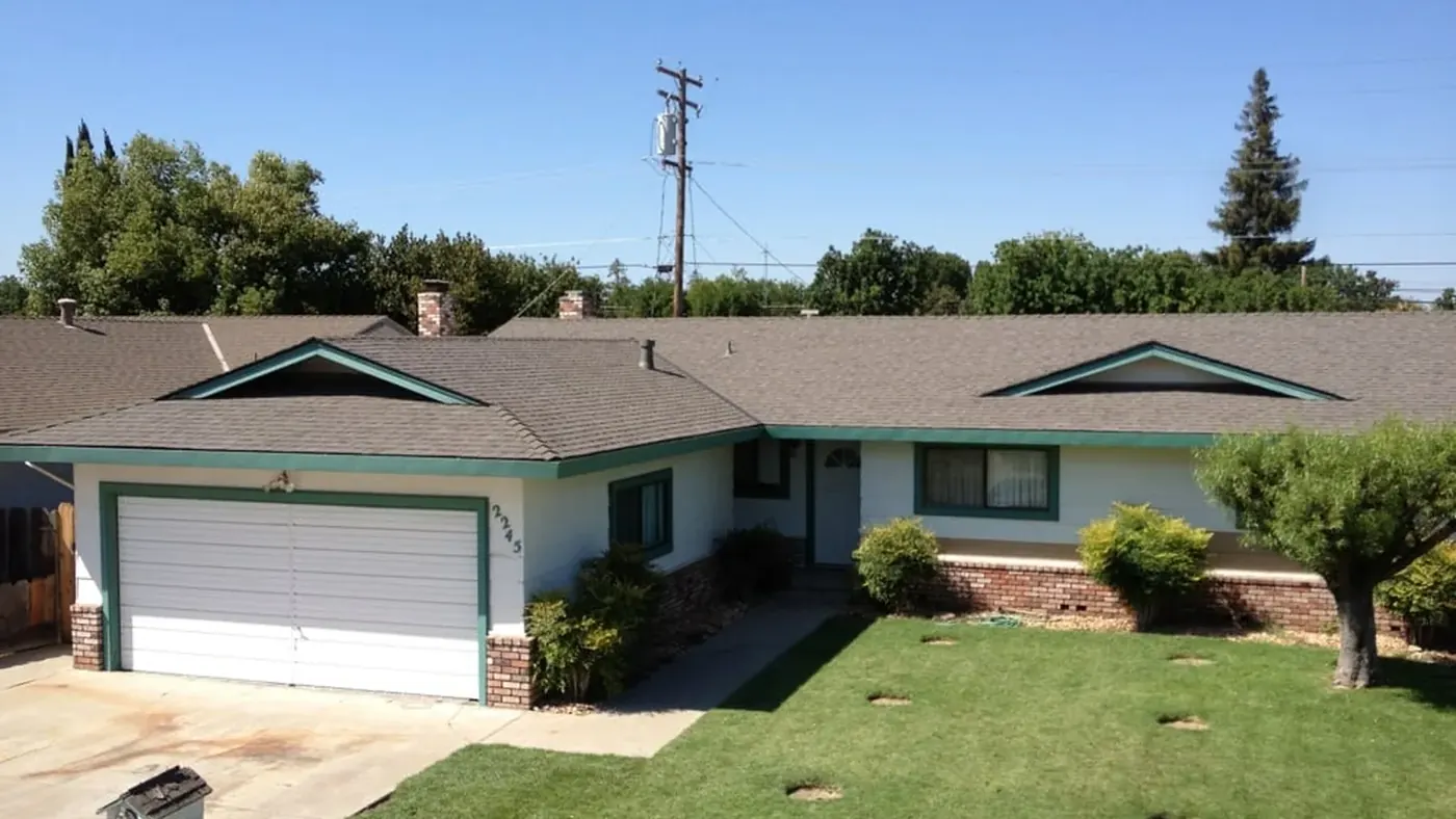 Single-story ranch home with a new dimensional shingle roof, green trim and a manicured lawn