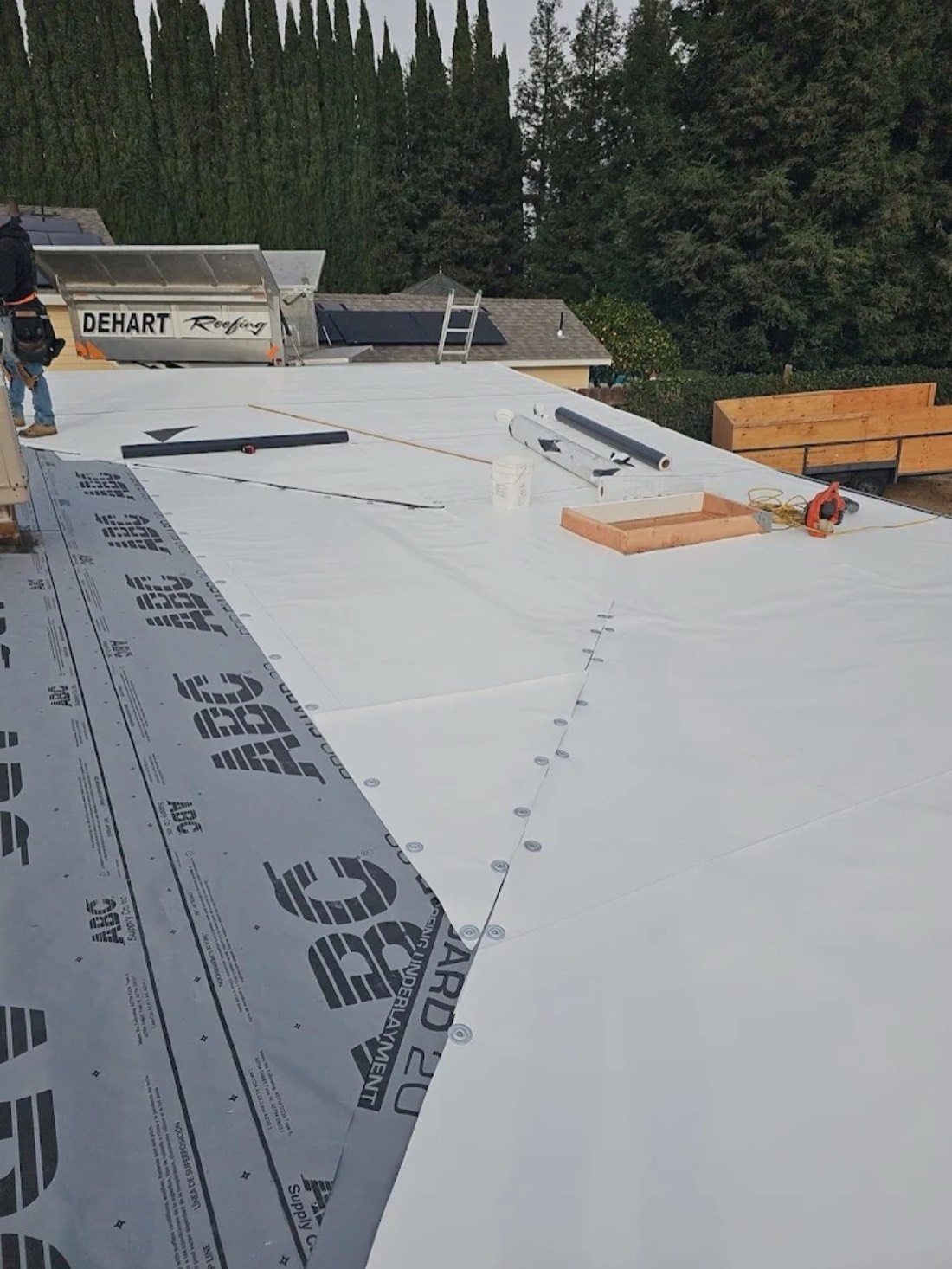 DeHart Roofing crew installing TPO single-ply membrane on a low-slope commercial roof in Stanislaus County