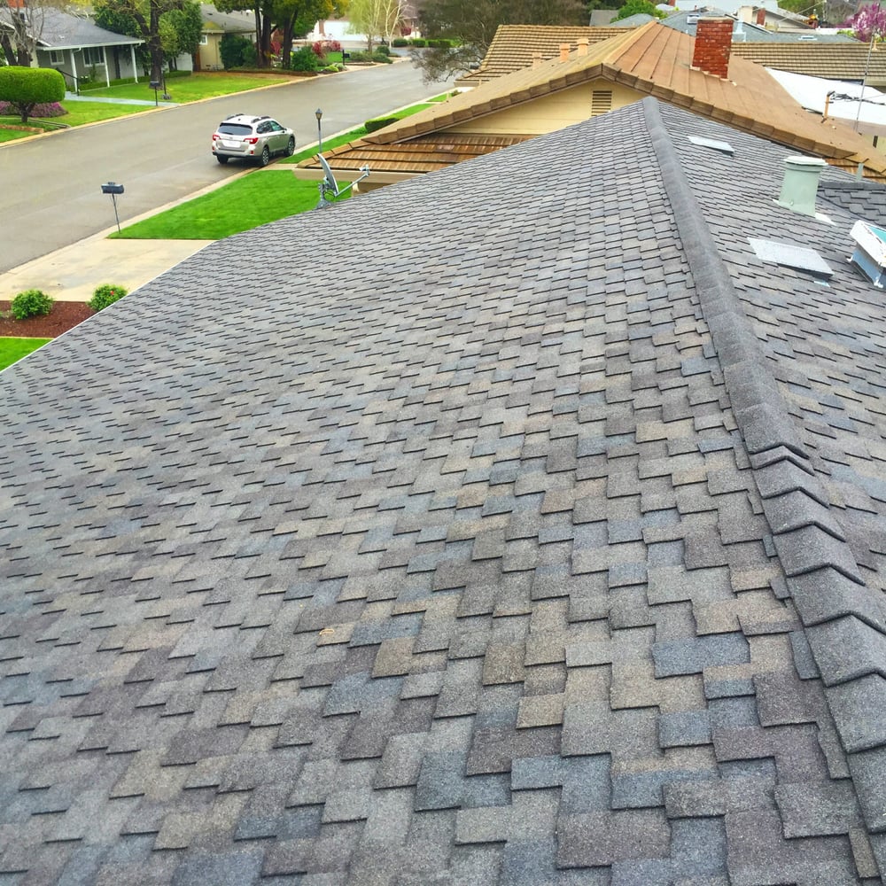 Close-up of a DeHart Roofing crew repairing damaged shingles and flashing on a Central Valley home